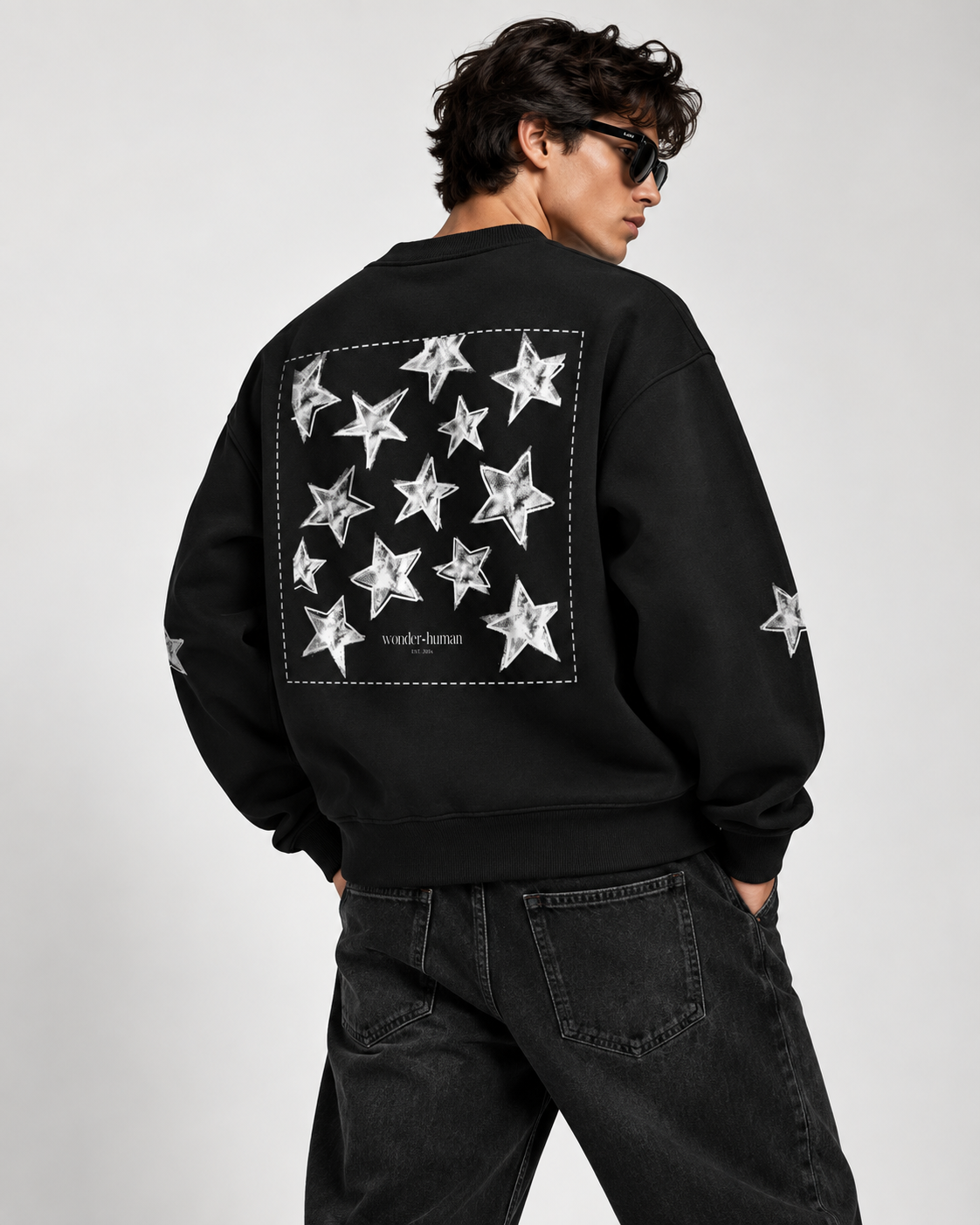 Model wearing black Celestial Archive Crewneck Sweatshirt, back view showing oversized celestial star graphic