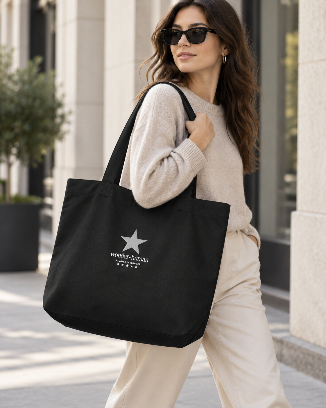 Woman carrying black North Star Tote Bag with cream outfit in an outdoor street-style setting