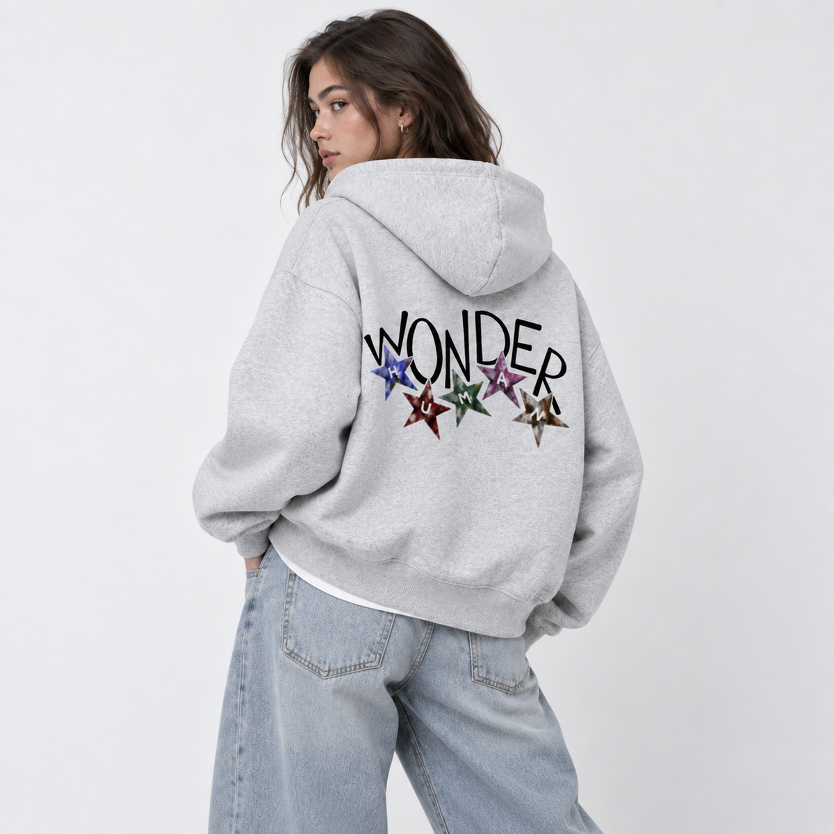 Female model wearing Flower Gray Wonder Zip Hoodie, back view in over-the-shoulder pose showing Wonder graphic with stars