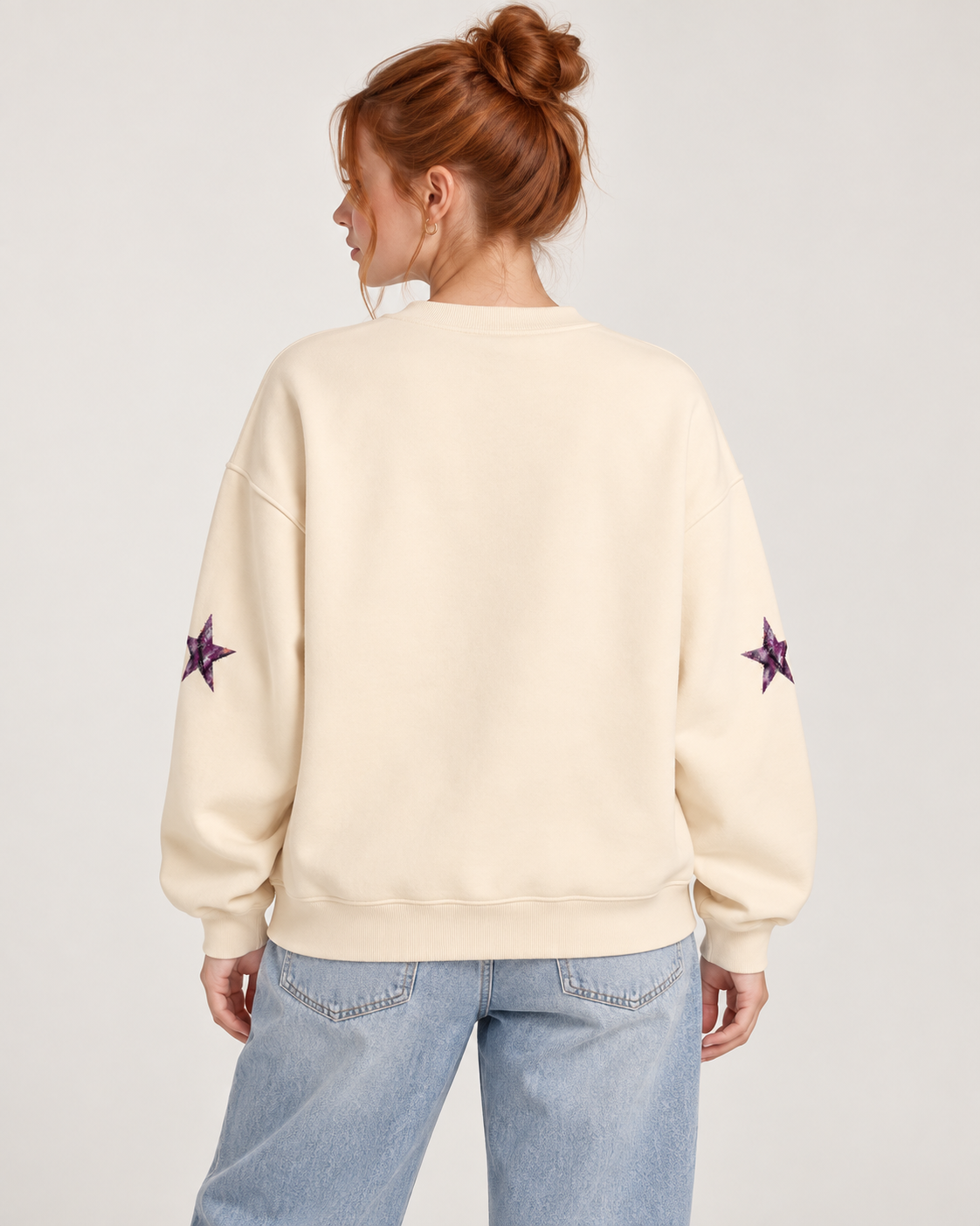 Red-haired model wearing Cream Apricot Amethyst Star Crewneck Sweatshirt with blank back and sleeve star details, back view