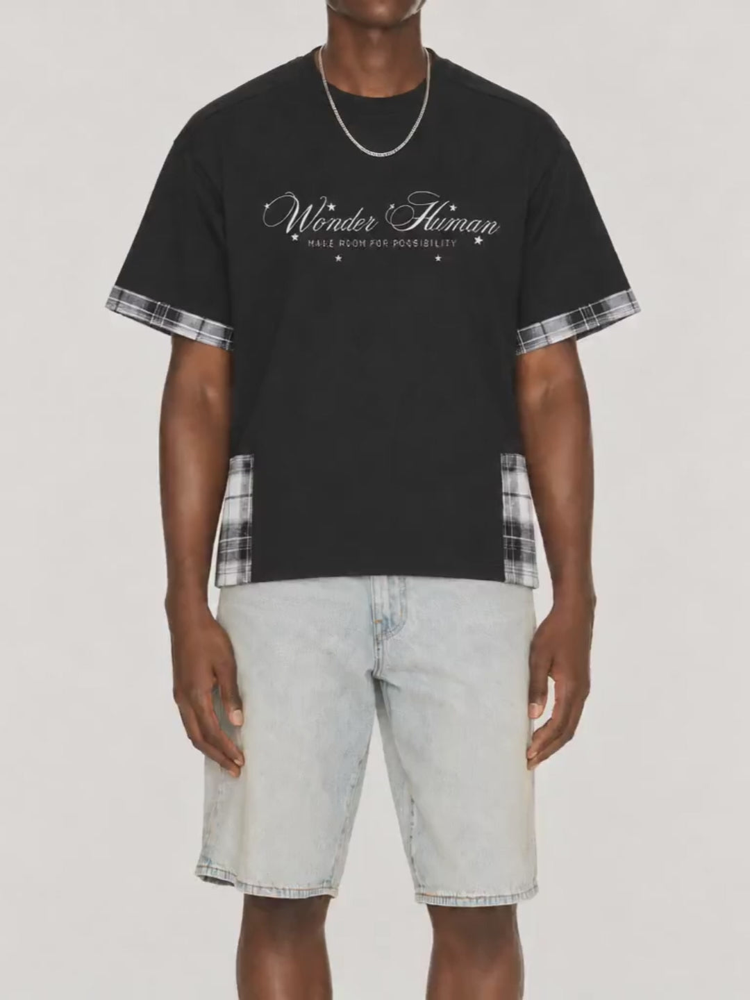Model wearing black Plaid Panel Tee with plaid trim and Wonder Human front graphic video.