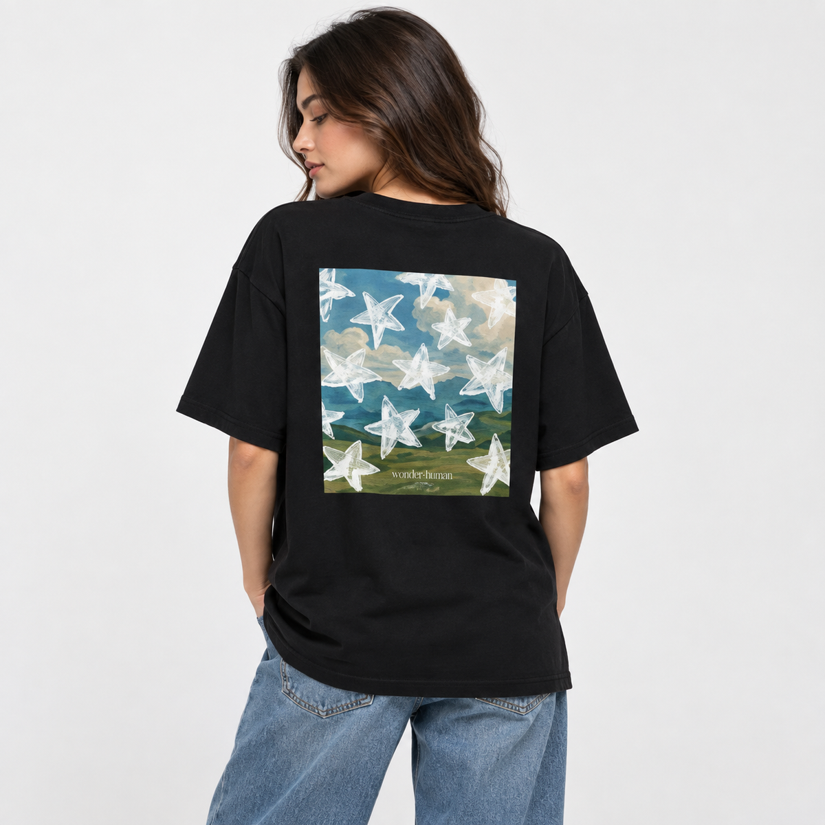 Female model wearing black Star Field Tee, back view showing star landscape graphic